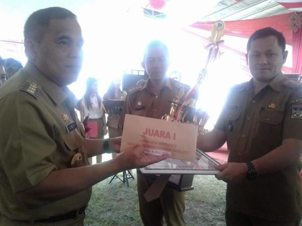 Hukum Tua Lucky Kasenda saat menerima trophy dari Bupati Minahasa