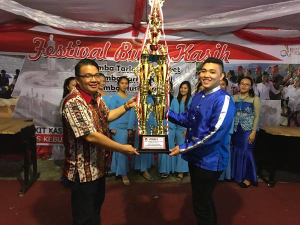 Kepala Dinas Pariwisata dan Kebudayaan Minahasa, Agustivo Tumundo menyerahkan trophy kepada peraih Juara I lomba Kolintang
